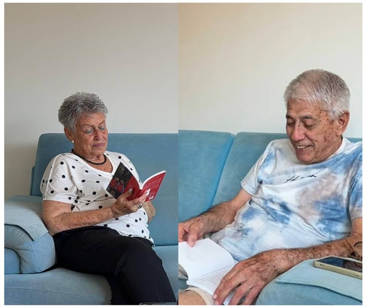Adina and Nehemia, each reading their own copy of their shared book, side by side.